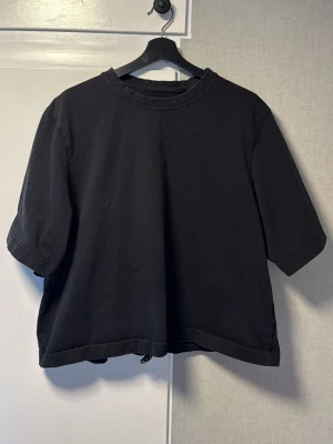 Svart oversized t-shirt i bomull - En svart oversized t-shirt med rund hals och korta ärmar. Tillverkad i mjuk bomull för en avslappnad och bekväm stil. Perfekt till jeans eller shorts för en enkel och clean look.