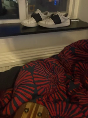 Vita sneakers med svart band - Säljer ett par vita sneakers med breda svarta band över vristen. Skorna har en klassisk låg profil och rundad tå. Passar perfekt till streetwear och har en stilren look som funkar till det mesta.