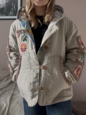 Beige egensydd jacka - En cool beige egensydd ”quiltjacka” med olika motiv. Passar bra som en vårjacka och har en original design. Jag på bilden brukar bära storlek XS som referens   Mått:   Axel: 46cm Bröst: 57cm Längd: 65cm Armlängd: 61cm