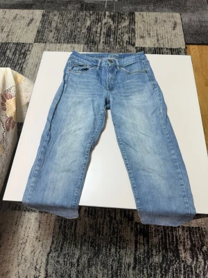 Ljusblå raka jeans - Säljer ett par ljusblå jeans med raka ben och klassisk femficksdesign. Jeansen har en snygg tvättad look och normal midja. Perfekta till en avslappnad stil och passar till det mesta. Materialet är troligtvis bomull med lite stretch.