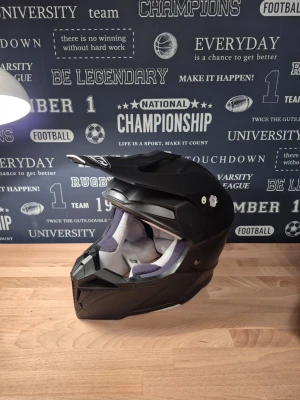 Svart HJC i50 crosshjälm, storlek M - Säljer en svart HJC i50 crosshjälm i storlek M (58 cm), vikt 1400g. Hjälmen har en snygg, kantig design med skärm framtill och ventilerad insida i grått. Perfekt för dig som gillar motocross eller kör moped. Ingår även googles från Thor i bra skick. Nypris ca 1500-2000kr. Köptes 2024 och har knappt blivit använd alls utan mest legat och samlat damm.