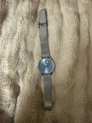 Silverfärgad meshklocka från Dapfor - Stilren klocka från Dapfor med silverfärgat mesharmband och rund urtavla i matchande ton. Klockan har minimalistisk design med tydliga markeringar och kvartsverk. Perfekt accessoar för dig som gillar en clean look.