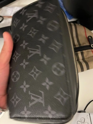 Louis Vuitton svart monogram handväska - Snygg svart handväska från Louis Vuitton med klassiskt monogrammönster i grått. Väskan har en rektangulär form och är tillverkad i tåligt lädermaterial. Perfekt accessoar för dig som gillar exklusiv och tidlös design. Köpt för 9500 men kan gå ner i pris!