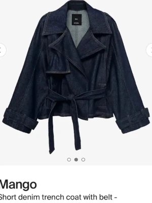 Kort trenchcoat i denim från Mango - Snygg kort trenchcoat i mörkblå denim från Mango. Jackan har bred krage, knytskärp i midjan och uppvikta ärmslut. Nypris: 1000. Använd 1 gång. 🤍