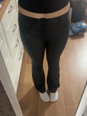 Svarta raka jeans med fickor - Säljer ett par svarta jeans med raka ben och klassiska fickor både fram och bak. Jeansen har en enkel design och är perfekta för dig som gillar en clean och stilren look. Materialet ser ut att vara bomull med lite stretch för extra komfort.