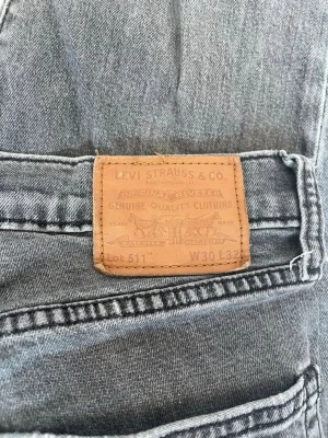 Grå Levi's 511  jeans - Snygga grå jeans från Levi's modell 511 med slim fit passform. Klassisk femficksdesign, läderpatch bak och diskret röd Levi's-tagg på bakfickan. Jeansen är tillverkade i bomull och polyester för en skön känsla och bra hållbarhet.