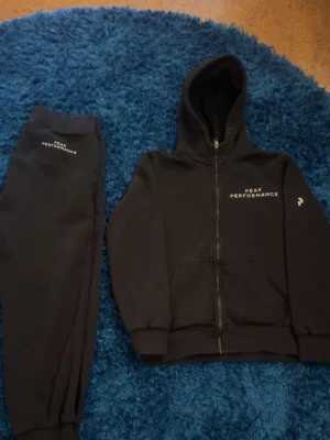 Svart loungewear-set Peak Performance - Mysigt svart loungewear-set från Peak Performance med zip-hoodie och matchande byxor. Hoodien har dragkedja, fickor och logga på bröstet. Byxorna har resår i midjan och muddar vid benslut. I ett riktigt bra skick nästan helt oanvänd, bara ett par gånger tvättade👌