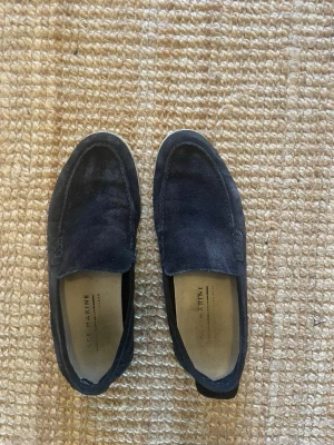 Mörkblå mocka loafers från Le Marine - Snygga mörkblå loafers från Le Marine i mjuk mocka. Klassisk slip-on modell med rundad tå och diskreta sömmar. Insidan är ljus och har tryckt logga. Perfekta för en stilren och avslappnad look.