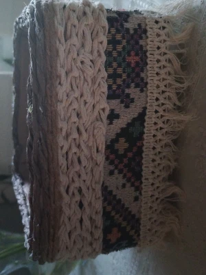 Bohemisk virkad tygväska med mönster - Unik boho-väska med virkade detaljer och färgglatt etnomönster på sidorna. Väskan har fransar längs kanterna och är gjord i tyg och garn i beige och multicolor. Perfekt accessoar för dig som gillar en kreativ och personlig stil.
