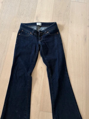 Mörkblå bootcut jeans - Snygga mörkblå bootcut jeans med låg midja. Jeansen har orangea sömmar. 