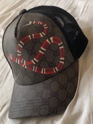 G.G keps med orm design  - FÖR FLER BILDER KOM IN I DM PÅ INSTA ”TRENDMARKNADEN” Helt ny och oanvänd. Kommer med tillhörande G.G tygpåse. Säljs enligt bilderna. Hör gärna av dig vid frågor eller intress