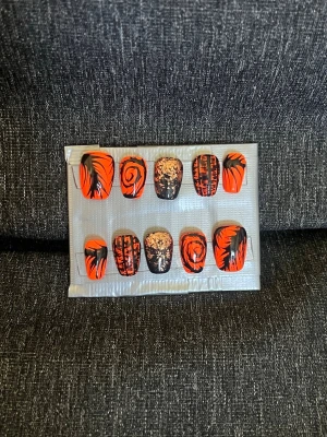 Press-on naglar || storlek L - Snygga press-on naglar i neon orange och svart med unika mönster som swirl, fjäder och guldiga detaljer. Naglarna har en kort, fyrkantig form. Perfekt för dig som vill ha en cool och edgy look. Storlek L, Det du får med dig : * Fil och manikyr pinne * nagellim klistermärken * 2 lappar av rengöring för naglar.