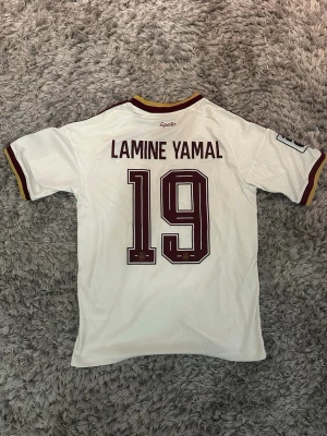 Spanien vm-bortatröja, Lamine Yamal  - Vit Spanien fotbollströja från Adidas med Lamine Yamal och nummer 19 på ryggen. Tröjan är storlek S och är helt ny med vm-loggorna på axlarna. 