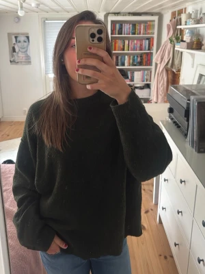 Mörkgrön oversized stickad tröja - Mysig mörkgrön stickad tröja i oversized modell med rund halsringning och långa ärmar. Perfekt för lager på lager och chill vardagsstil. Tröjan har ribbade muddar vid ärmslut och nederkant. Passar dig som gillar en avslappnad look.
