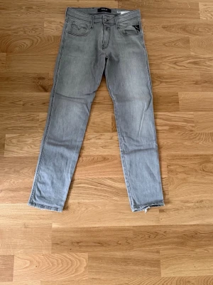 Ljusgrå slim fit jeans Replay 30/30 - Snygga ljusgrå slim fit jeans från Replay med klassisk femficksdesign och råa kanter vid bensluten. Jeansen har en modern tvätt och detaljerade sömmar på bakfickorna. Perfekta för en trendig och avslappnad stil. Priset ej hugget i sten. Hör av vid funderingar