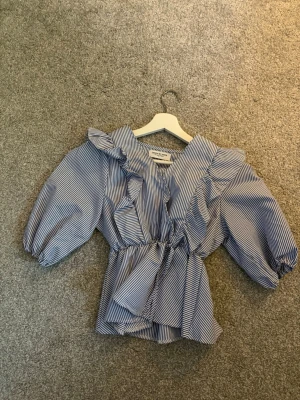 Blårandig volangblus från Design by Amor!💓💓 - Fin  blus från Design by Amor, storlek S. Bara använd 1 gång. Perfekt till sommaren! Priset kan diskuteras.🩷🩷