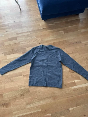 Grå sweatshirt från Hugo Boss - En stilren grå sweatshirt från Hugo Boss med rund halsringning och diskret broderad logga på bröstet. Tröjan har långa ärmar och är gjord i mjukt bomullsmaterial. Perfekt för en avslappnad look.