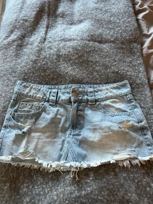 Ljusblå jeanskjol med slitningar från Gina Tricot - Kort jeanskjol, knappt använd. Gina Tricot, storlek M 14+