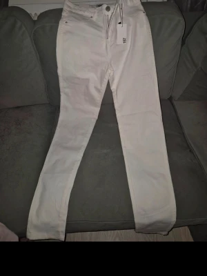 Vita raka jeans från Lindex - Snygga vita jeans från lager157 med rak passform och klassisk femficksdesign. Jeansen har normalhög midja och är tillverkade i ett mjukt bomullsmaterial med lite stretch för extra komfort. Perfekta att styla med en crop top eller hoodie.