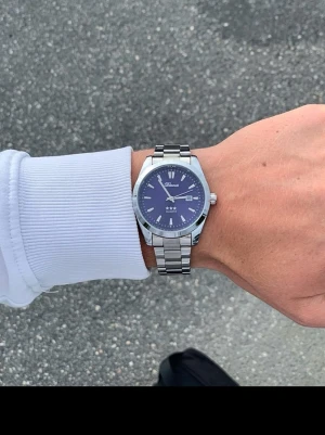 Blå klocka från Doventi med stållänk - 🌟 Doventi - Helt ny och oanvänd klocka i toppskick!  🎁 Levereras komplett med originalbox. ✨ Perfekt skick, garanterat utan defekter. ⚙️ Justering för optimal passform. 🚀 Snabb leverans samma dag – direkt till dig!