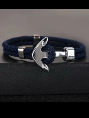 Marint armband med ankardetalj - Snyggt armband i marinblått rep med en blank silverfärgad ankare som lås. Armbandet har stilrena metalliska detaljer och en modern, nautisk känsla. Perfekt accessoar för dig som gillar havsinspirerad stil.