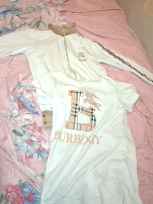 Vit Burberry t-shirt med logga.  - Burberry kofta och T-shirt till sammans kosta 2000kr.Varje en månad kommer jag sänka priset om ingen köpa. Det kan passa till 13år om du väger för lite.