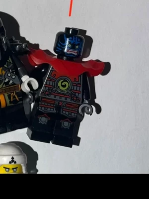 LEGO Ninjago minifigurer och tillbehör - Samling med LEGO Ninjago minifigurer i olika färger som röd, blå, svart, vit och grön. Inkluderar drakhuvud, hattar, hjälmar och vapen. Figurerna har detaljerade tryck och vissa har rustningar eller mantlar. Perfekt för dig som gillar att bygga och samla Ninjago-karaktärer.