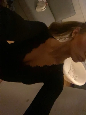 Svart intimissimi tröja  - Snygg svart långärmad topp med v-ringning och spetsdetaljer både vid halsringningen och ärmsluten. Perfekt för dig som gillar en enkel men ändå elegant look. Tunn och mjuk i materialet, sitter snyggt på kroppen.