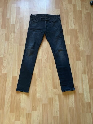 Svarta slim Glenn jeans, Jack & Jones W31 L34 - Snygga svarta slim fit jeans med klassisk femficksdesign och dragkedjegylf. Jeansen har en smal passform och är tillverkade i ett stretchigt denimtyg som ger bra komfort och rörelsefrihet. Perfekta för en trendig och avslappnad stil.