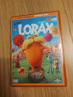 Lorax DVD film - Säljer en DVD med filmen Lorax från skaparna av Dumma Mej. Omslaget är orange och motivet visar Lorax och flera färgglada karaktärer från filmen. Filmen är animerad och har svensk text och tal. Perfekt för dig som gillar familjefilmer och animation.