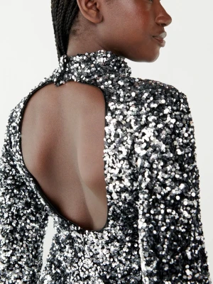 Glittrig svart paljettklänning - Used only once. Absolutely stunning and comfortable. Snygg svart klänning täckt av glittrande paljetter med lång ärm och öppen rygg. Hög hals och figurnära passform, perfekt för dig som vill sticka ut. Klänningen har en kort längd och är tillverkad i syntetmaterial.