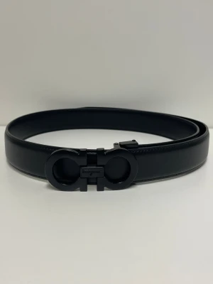 Ferregamo Bälte - Snyggt svart skärp från Salvatore Ferragamo med ikoniskt dubbel-Gancio-spänne i svart metall. Bältet är gjort i slätt skinn och har en stilren, minimalistisk design som passar till många olika looks.Helt nytt aldrig använd storlek 110