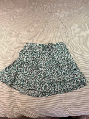 Blommig kjol ZARA - Kjol från Zara med blommigt mönster. Inbyggda shorts!! ☀️Kjolen har volangdetaljer och resor med knytning i midjan. 