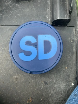 Blå snusdosa med SD-logga - Säljer en rund snusdosa i plast med blå färg och tydlig SD-logga på locket. Dosan har ett enkelt lock som går att öppna och stänga smidigt. Perfekt för dig som vill ha en personlig och unik snusdosa. Ge bud 