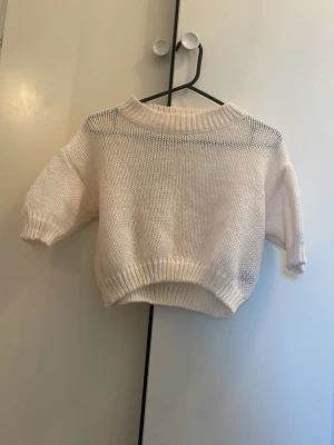 Vit oversize stickad tröja - Säljer en vit stickad tröja i oversize-modell med bred ribbad mudd vid hals, ärmslut och nederkant. Tröjan har en avslappnad passform och är gjord i mjukt material, perfekt för en chill look. Skulle nog säga mer som en 34 