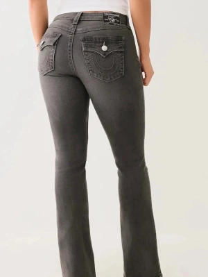 True Religion jeans Becca mid - Säljer ett par gråa bootcut jeans från True Religion med ikoniska kontrastsömmar och snygga ficklock bak med silverfärgade knappar. Jeansen har normal midja och är tillverkade i stretchigt denim för skön passform.
