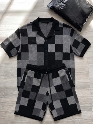 Premium Stickat Set - Svart - Snygga shorts med rutigt mönster i svart och olika nyanser av grått. De har elastisk midja med snörning och sidofickor. Materialet ser ut att vara mjukt och stickat, perfekt för en avslappnad stil. Matcha med en enkel t-shirt eller hoodie för en cool look.