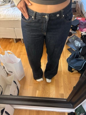 Mörkblå raka jeans - Snygga mörkblå jeans med raka ben och klassisk femficksmodell. Jeansen har kontrastsömmar och lågmidja. Perfekta för en avslappnad och trendig stil.