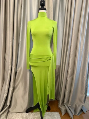 Fest klänning med öppen rygg och slits - Asos design Limegrön klänning med , långa ärmar och snygg knytning i midjan. Klänningen har en hög slits och en dramatisk öppen rygg med knappstängning i nacken. Tillverkad i stretchigt material som sitter tight och markerar figuren.