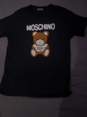 Svart Moschino t-shirt  - Svart t-shirt från Moschino, väldigt skönt material och väldigt bra passform. Storleken är M men passar S. Har ej använt den!