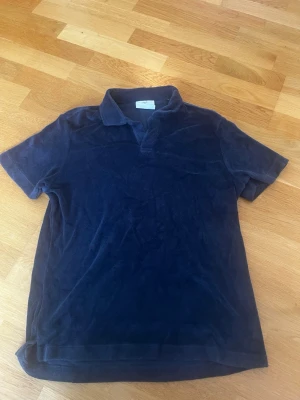 Mörkblå frotté polotopp - Mjuk och skön mörkblå polotopp i frotté med klassisk krage och korta ärmar. Perfekt för en avslappnad och trendig look. Enkel att matcha med både jeans och shorts.