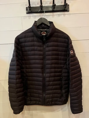 Svart pufferjacka från Colmar - Snygg svart pufferjacka från Colmar med diskret logga på ärmen och hög krage. Jackan har dragkedja framtill, två sidofickor med dragkedja och quiltad design finns även en innerficka också . Perfekt för kalla dagar och riktigt skön att bära. Materialet är lätt och isolerande.hör av er för fler frågor pris kan sänkas vid snabb affär 🤝