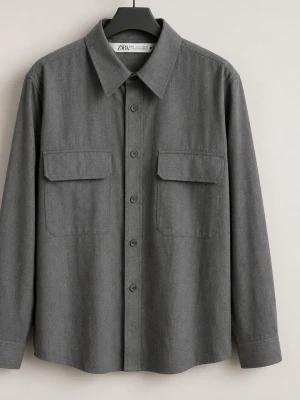 Grå overshirt från Zara - Stilren grå overshirt från Zara med klassisk krage, två stora bröstfickor med lock och knäppning framtill. Skjortan har lång ärm och är tillverkad i ett mjukt material som passar perfekt för lager på lager. Enkel att matcha med olika outfits.