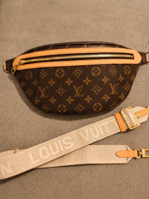 🤎 High Rise Monogram Belt Bag 🤎 - A modern classic featuring iconic monogram canvas, natural leather details, gold-tone hardware, and an adjustable jacquard strap with room for your phone, wallet, keys, sunglasses, and other daily essentials.  Wear it crossbody, on the shoulder, or around the waist.  ✨ Monogram canvas ✨ Natural leather trim ✨ Gold-tone hardware ✨ Adjustable strap included ✨ Spacious zip-top compartment One of the most popular luxury-inspired belt bag silhouettes  📦 Adjustable strap included 💌 Message for more ph