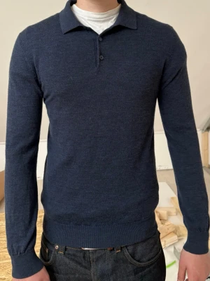 Mörkblå stickad pikétröja - Tvär fett stickad merinoull pikétröja från John Henric. Modellen är 185cm men brukar vanligtvis bära M.