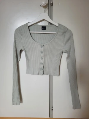 Topp Gina Tricot - Ljusgrön croppad topp från Gina Tricot med ribbad struktur och långa ärmar.