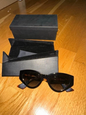 Christian Dior solglasögon brun mönstrad - Snygga solglasögon från Christian Dior med brunmelerat sköldpaddsmönster och breda skalmar. Kommer med original svart fodral och låda. Perfekt accessoar för att lyfta din stil. Nästintill nytt skick.