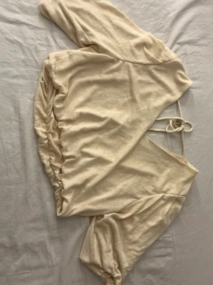 Gul croppad omlottopp med knyt - Trendig gul croppad omlottopp med knyt i ryggen och ballongärmar. Toppen har en avslappnad passform och är tillverkad i mjukt bomullsmaterial. Perfekt för dig som gillar en stilren och modern look. Vet inte storlek men skulle säga S/M