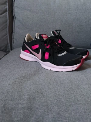 Nike svartrosa sneakers med meshdetaljer - Säljer ett par snygga och bekväma Nike-träningsskor i svart med rosa detaljer. Perfekta för träning, promenader, gymmet eller som bekväma vardagsskor.   Nike Comfort Footbed för extra komfort Lätta och sköna på foten Snygg svart design med rosa detaljer Storlek 37,5 Bra skick och mycket användning kvar  Skorna sitter bekvämt på foten och passar lika bra till träning som till vardags.   📸 Fler bilder och information skickas gärna.