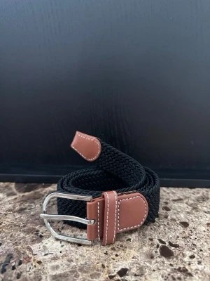 Svart flätat bälte - Tja jag säljer ett mycket fint flätat skärp. Det är helt nytt och är ca 105-110cm och 3,5cm bret, men kan bli mycket längre pga det elastiska materialet. Det finns flera skärp i min profil om du skulle vara sugen och desto mer du köper desto billigare blir det.